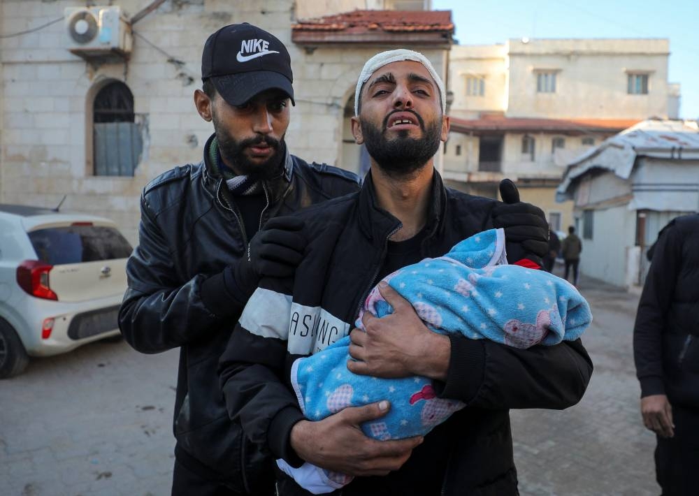 Palestinian man Belal Kullab, wounded in an Israeli strike that killed his infant son Adnan, carries Adnan's body, at Al-Ahli Arab Baptist hospital in Gaza Cit, on Wednesday. REUTERS