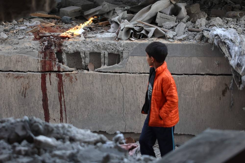 A boy walks past blood stains at the site of an Israeli strike on a house in Khan Yunis, in the southern Gaza Strip, on Wednesday. AFP 