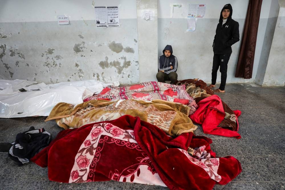 A mourner sits near the bodies of Palestinians killed in Israeli strikes, at Al-Ahli Arab Baptist hospital in Gaza City, on Wednesday. REUTERS