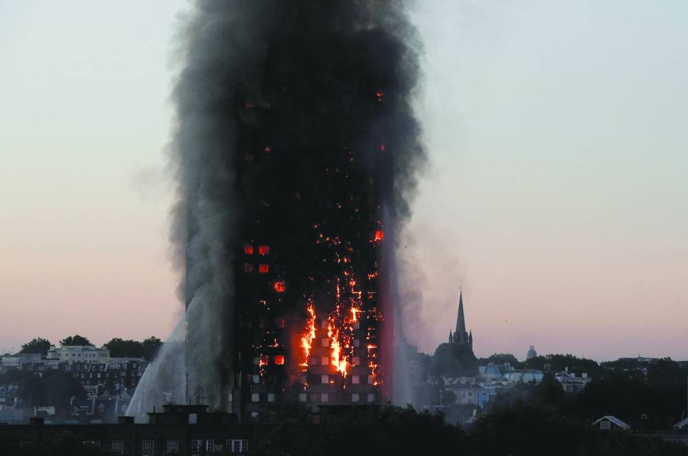 Flames and smoke billow as firefighters deal with a fire in the Grenfell Tower apartment block in West London on June 14, 2017. 