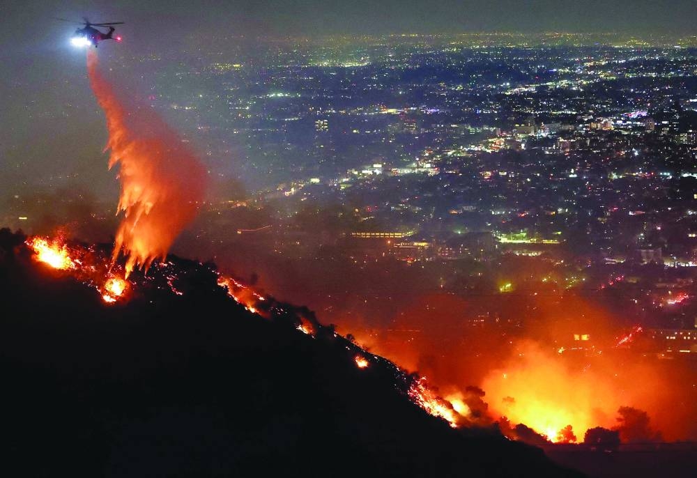 
A firefighting helicopter drops water as the Sunset Fire burns in the Hollywood Hills with evacuations ordered on Wednesday in Los Angeles, California. (AFP) 