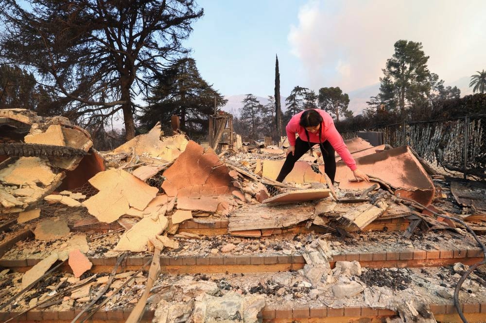Conchita Gomez inspects damage after the Eaton Fire tore through a neighborhood, on Friday. REUTERS