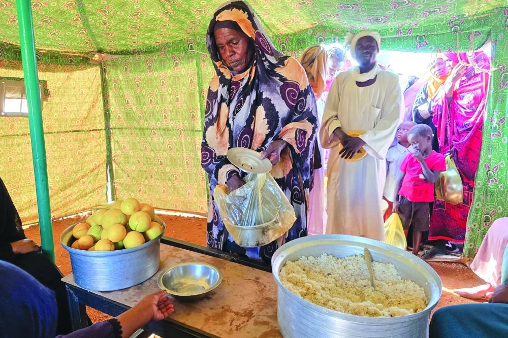 A woman collects food at a location set up by a local humanitarian organisation to donate meals and medication to people displaced by the war in Sudan, in Meroe in the country's Northern State.