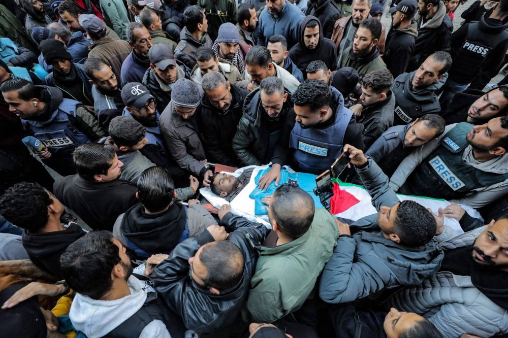Mourners and colleagues surround the body of Palestinian freelance cameraman Saed Abu Nabhan, a day after he was killed by Israeli forces in the Nuseirat camp in the central Gaza Strip during his funeral on Saturday. AFP