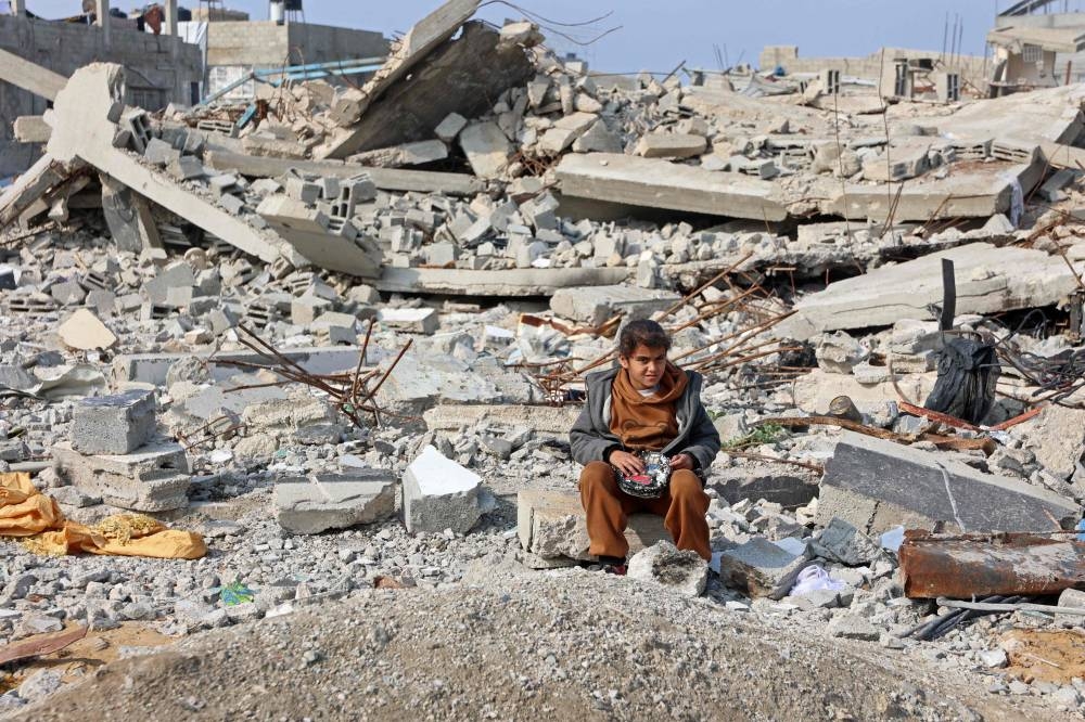A Palestinian girl sits amid the rubble of buildings destroyed in Israeli airstrikes, in Gaza City on Saturday. AFP