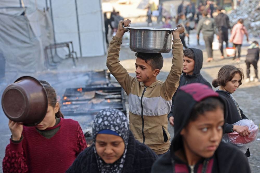 A Palestinian boy walks after receiving aid food being distributed by charitable hospices in Gaza City on Saturday. AFP
