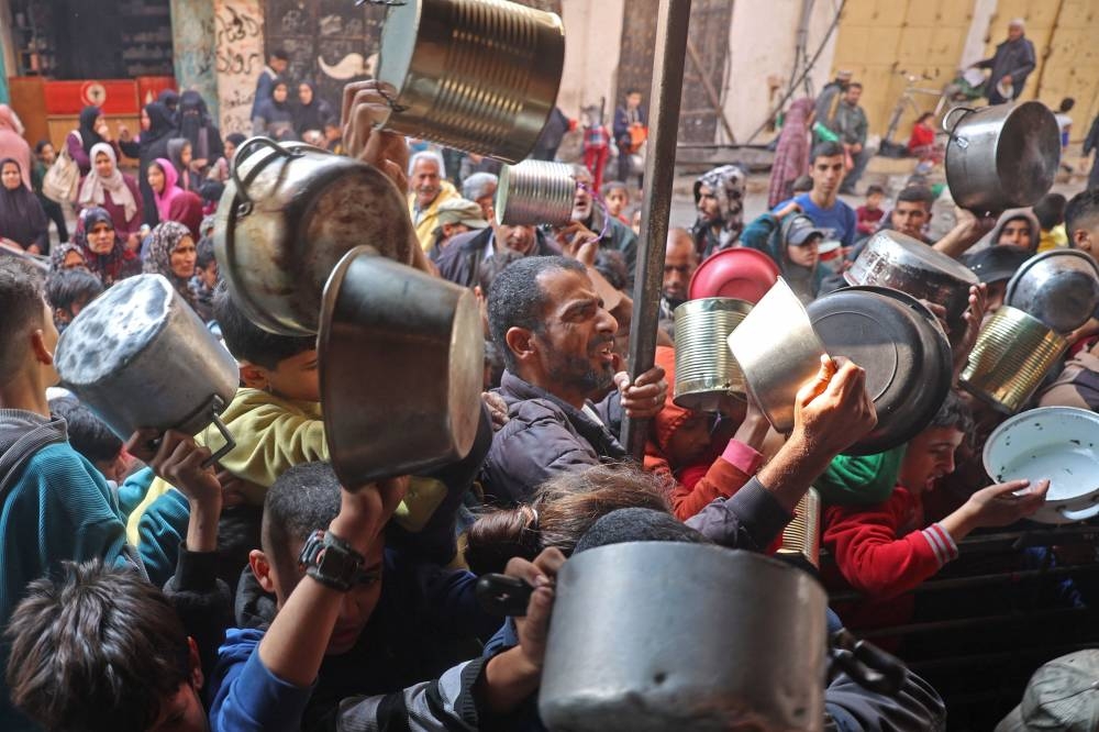 Palestinians gather to receive aid food being distributed along the roadside at the Nuseirat refugee camp in the central Gaza Strip on Saturday. AFP