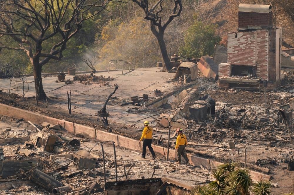 Firefighters survey the remains of homes following the Palisades Fire in the Pacific Palisades neighborhood in Los Angeles, California, on Friday. REUTERS