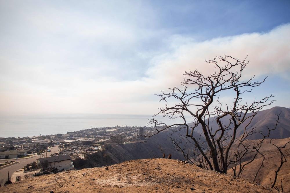 Wildfire smoke and burned houses are seen from the Palisades Fire on Friday in the Pacific Palisades neighborhood of Los Angeles, California.  AFP