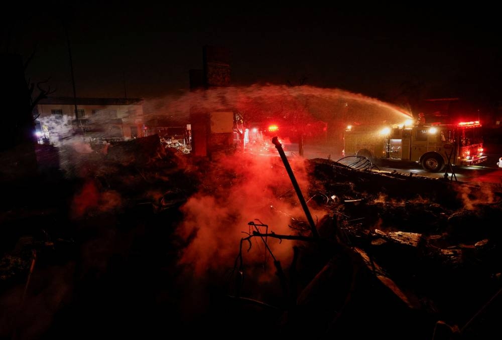 Firefighters hose down a hotspot at a commercial building that burned down during the Eaton Fire, in Altadena, California, on Friday. REUTERS