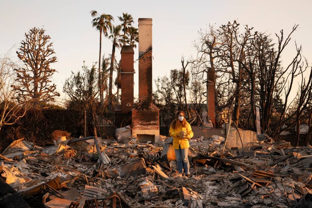 Stacy Weiss holds pieces of fine china set that she found intact after her home was destroyed by the Palisades Fire in the Pacific Palisades neighborhood in Los Angeles, California, on Saturday. REUTERS