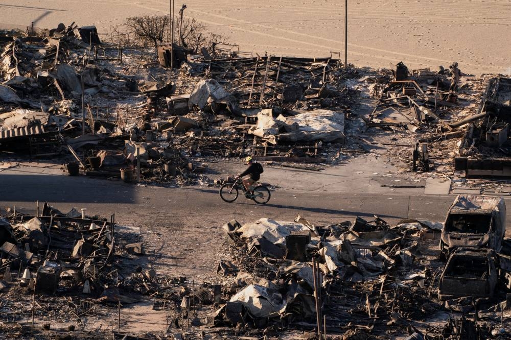 A cyclist passes homes destroyed by the Palisades Fire, in the Pacific Palisades neighborhood in Los Angeles, California, on Sunday. REUTERS