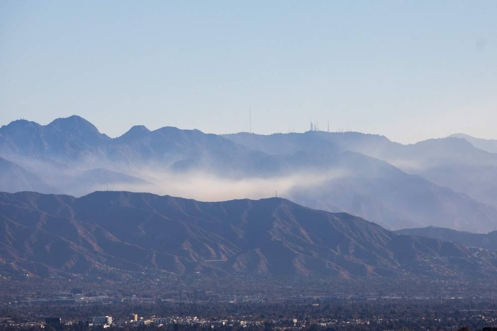 Wildfire smoke in the mountains of Angeles National Forest seen from Encino Hill, where Palisades fire is still burning on Sunday in Encino neighborhood of Los Angeles, California. AFP