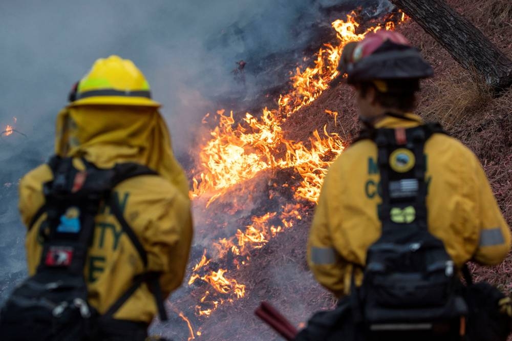 Firefighters watch as the Palisades Fire, one of simultaneous blazes that have ripped across Los Angeles County, burns at the Mandeville Canyon, a neighborhood of Los Angeles, California, on Saturday. REUTERS