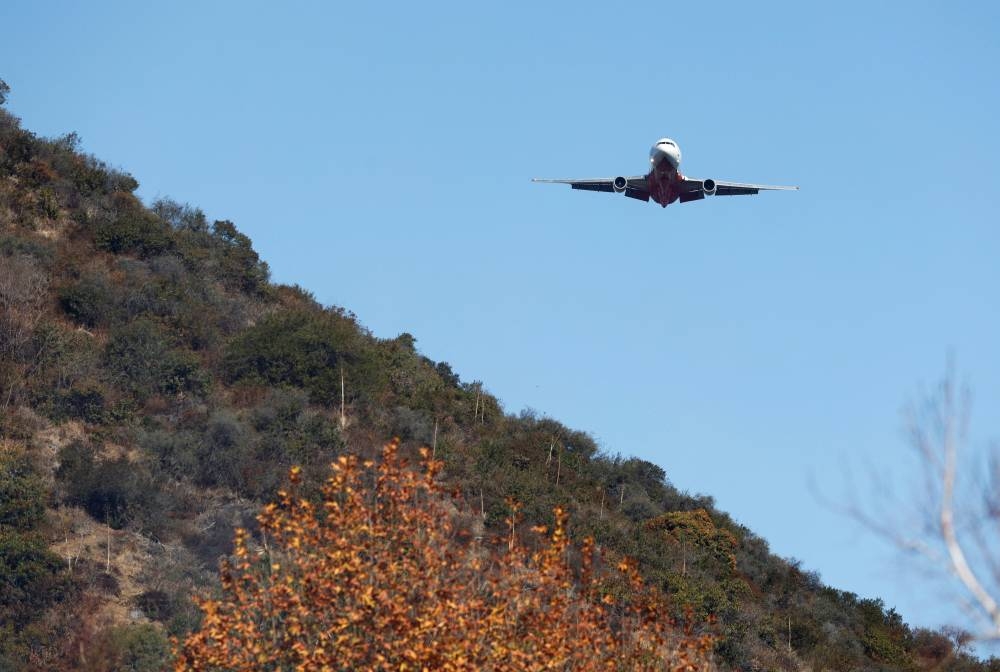 A plane prepares to drop retardant on the Palisades Fire, one of simultaneous blazes that have ripped across Los Angeles County, along Mandeville Canyon, in the Encino neighborhood of Los Angeles, California, on Saturday. REUTERS