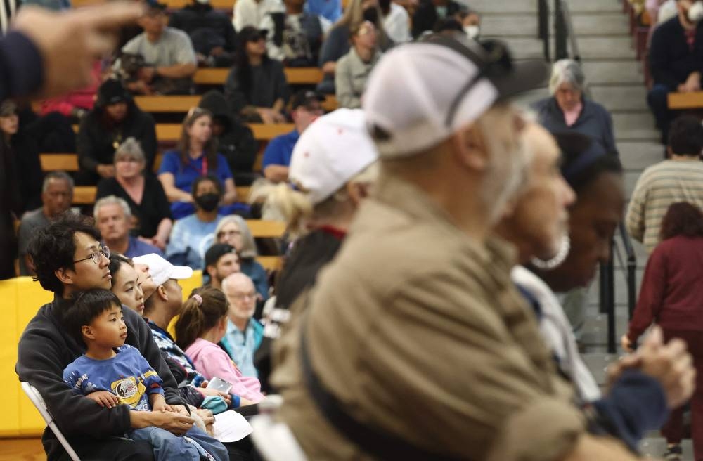People listen to a speaker at a community meeting for those impacted by the Eaton Fire as wildfires cause damage and loss through LA region on Sunday in Pasadena, California. AFP