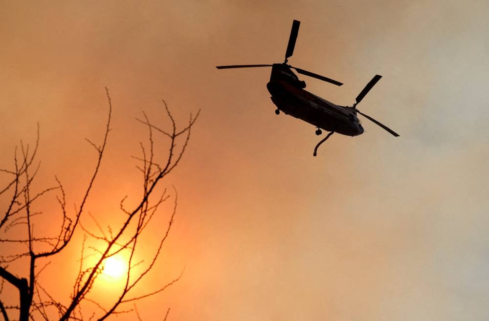 A helicopter flies over the Palisades Fire, one of several simultaneous blazes that have ripped across Los Angeles County, along Mandeville Canyon, in the Encino neighborhood of Los Angeles, California, on Saturday. REUTERS. 