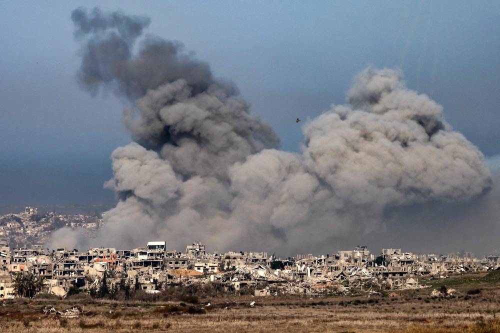 Smoke plumes rising from explosions above destroyed buildings in the northern Gaza Strip, on Monday.  AFP
