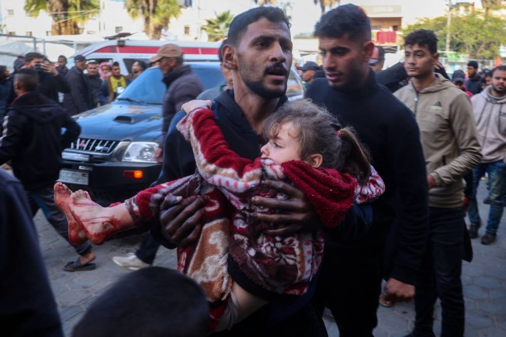 A Palestinian man carries an injured girl into a hospital after an Israeli strike, in Deir el-Balah in the central Gaza Strip, on Tuesday. AFP