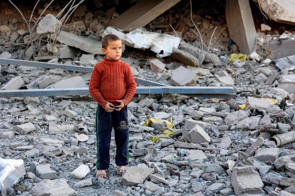 A child stands amidst debris and rubble by a collapsed building at the site of Israeli bombardment on a residential block in Jalaa Street in Gaza, City on Tuesday. AFP