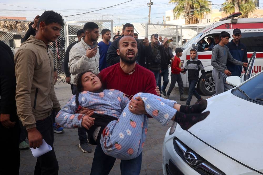 A Palestinian man carries an injured girl into a hospital after an Israeli strike, in Deir el-Balah in the central Gaza Strip, on Tuesday. AFP