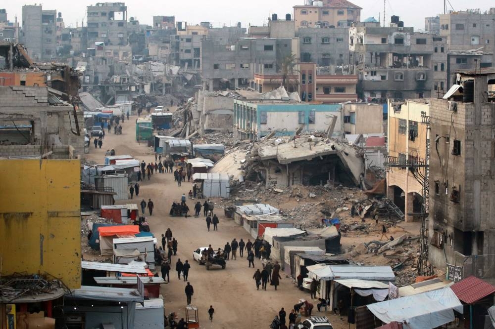 People walk past stalls selling goods amid the rubble of buildings destroyed during previous Israeli strikes, in Khan Yunis in the southern Gaza Strip on Wednesday. AFP