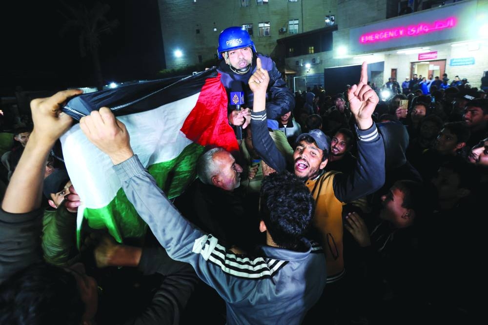 Palestinians celebrating news on a ceasefire with Israel, carry Al Jazeera correspondent Ashraf Amrah as he reports live in Deir Al-Balah in the central Gaza Strip, Wednesday