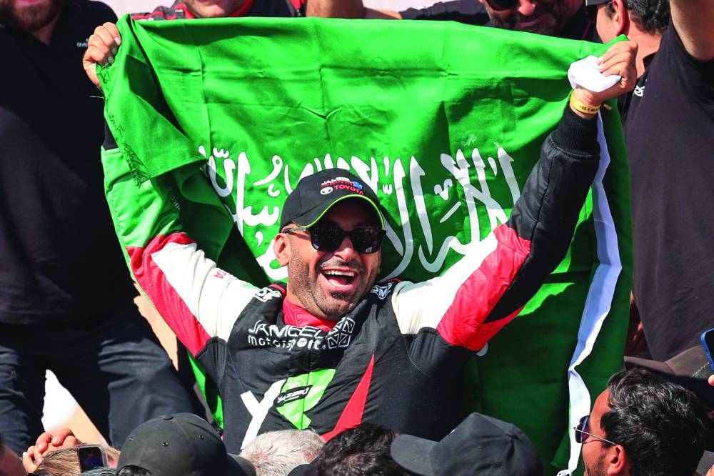 Yazeed al-Rajhi celebrates after winning the Dakar Rally title in the car category at the end of the 12th and last stage in Shubaytah, Saudi Arabia, on Friday. (AFP)