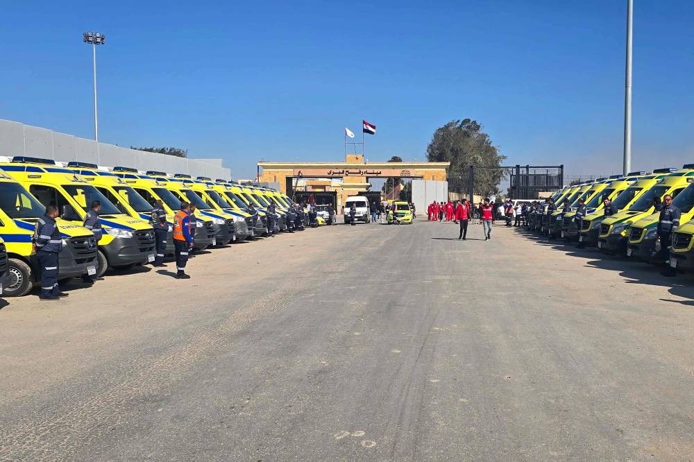 Paramedics and ambulances wait on the Egyptian side of the Rafah border crossing with the Gaza Strip on Saturday, to enter into Gaza following the Israeli cabinet's approval of a ceasefire deal amid the ongoing war between Israel and Hamas. AFP