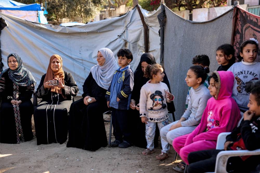 Family members of Abdelrahman al-Miqdad, 49, a Palestinian prisoner charged with planning attacks on Israelis and detained by Israel in Bethlehem in 2004, gather together to await news of his release at a displacement camp in Deir el-Balah in the central Gaza Strip on Saturday, following the Israeli cabinet's approval of a ceasefire dear amid the ongoing war between Israel and Hamas. AFP