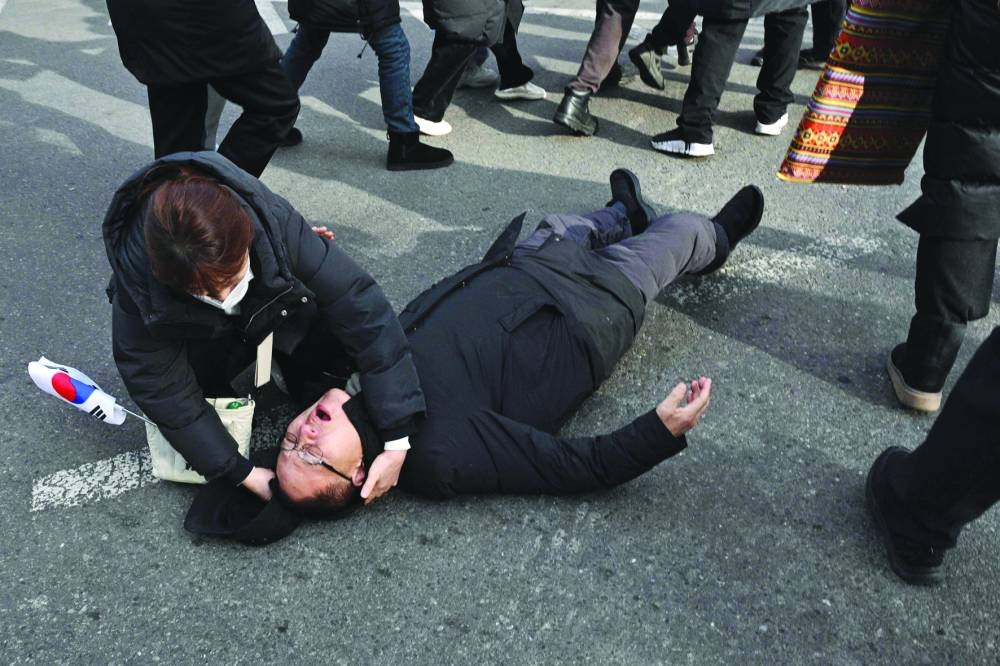 
A man lies injured on a road after a fall as pro-Yoon supporters stand off with police outside the Seoul Western District Court. 