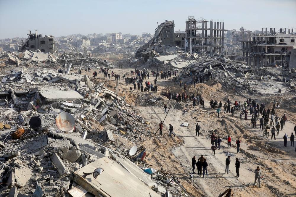 Displaced Palestinians walk past the rubble as they attempt to return to their homes, on the day the ceasefire between Israel and Hamas takes effect, in the northern Gaza Strip, on Wednesday. REUTERS