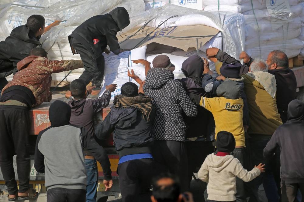 People gather to collect humanitarian aid after trucks arrived in the Gaza Strip via the Kerem Shalom crossing, also known as Karem Abu Salem, on Wednesday. AFP