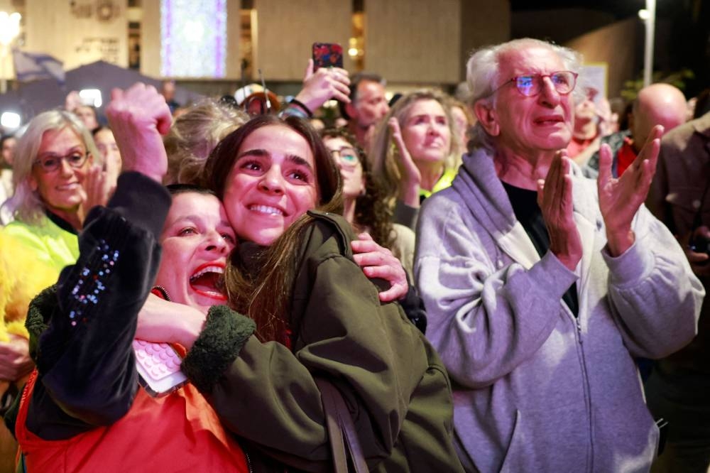 Supporters and relatives of hostages held captive in the Gaza Strip react while watching a live television broadcast on the release of Israeli hostages, at the Hostages Square in Tel Aviv, on Sunday. AFP
