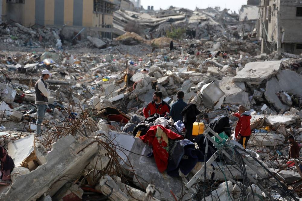 Displaced Palestinians sit with their belongings amid the devastation upon their return to central Rafah in the southern Gaza Strip, SUnday.