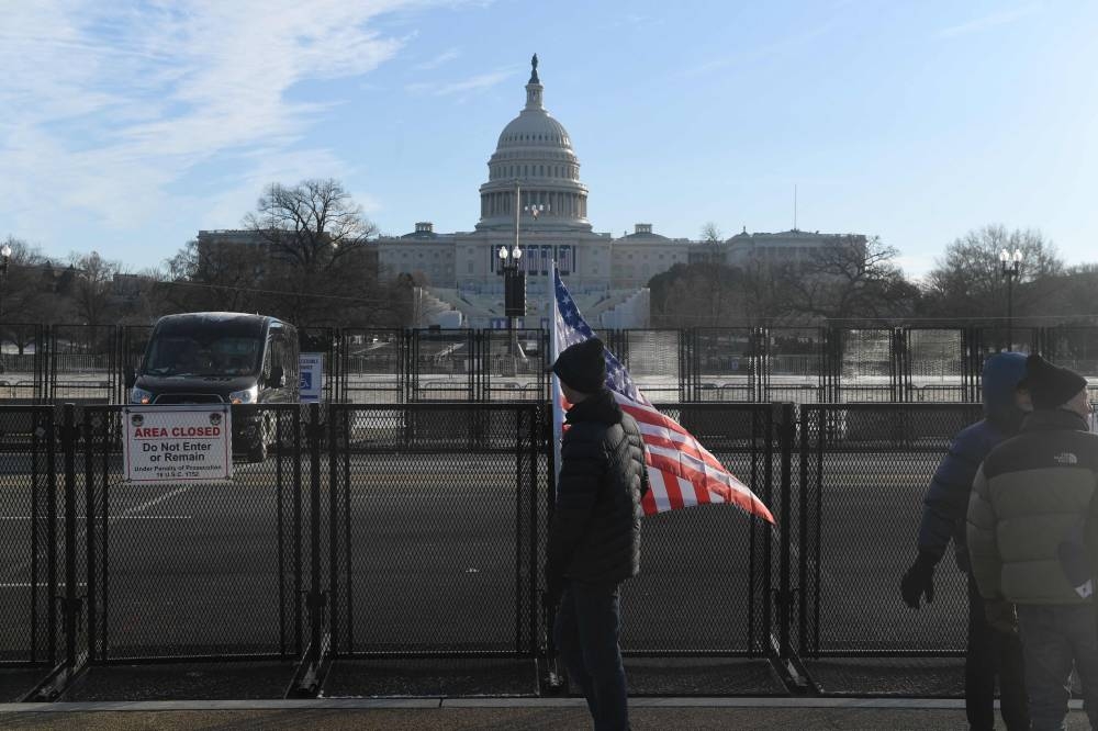 A man carries an American flag outside  the security perimeter near the US Capitol on inauguration day, where US President-elect Donald Trump will be sworn in as the 47th US President, in Washington, DC, on Monday. AFP