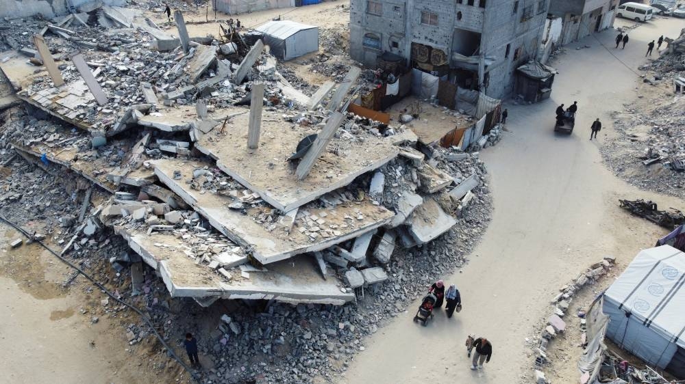 A drone view shows Palestinians walking past the rubble of houses and buildings destroyed in Israeli strikes during the war, in Khan Younis in the southern Gaza Strip, on Monday. REUTERS