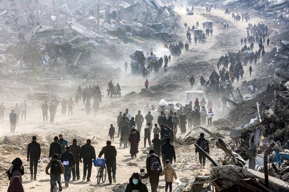 People walk past the rubble of collapsed buildings along Saftawi street in Jabalia in the northern Gaza Strip, on Monday. AFP 