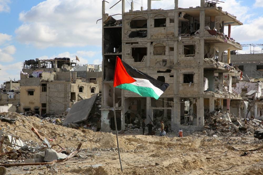 A Palestinian flag flutters near the rubble of houses and buildings destroyed during the war, in Rafah in the southern Gaza Strip, on Monday. REUTERS