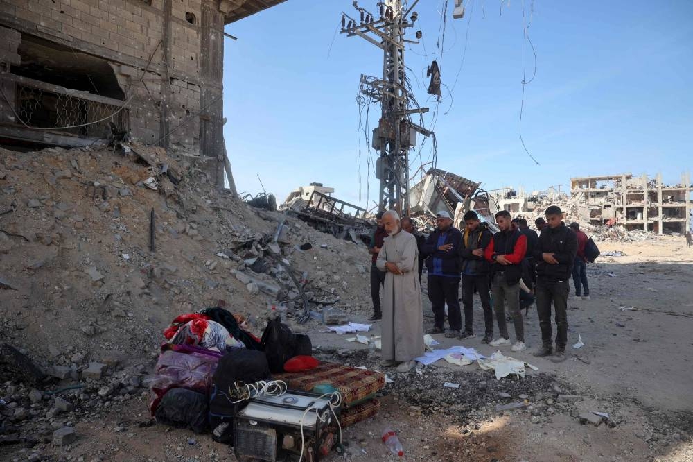 Palestinians pray next to building rubble in a ruined neighbourhood in Gaza's southern city of Rafah on Monday, as residents return following a ceasefire deal a day earlier between Israel and the Palestinian Hamas group. AFP