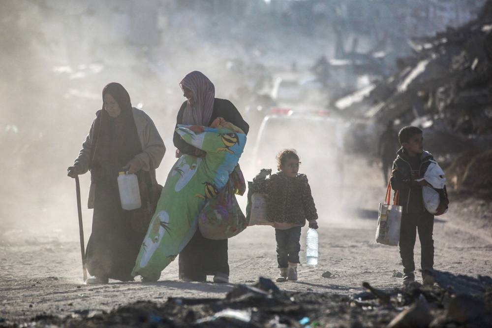 Palestinians carrying their belongings walk amidst building rubble in a ruined neighbourhood of Gaza's southern city of Rafah on Monday. AFP