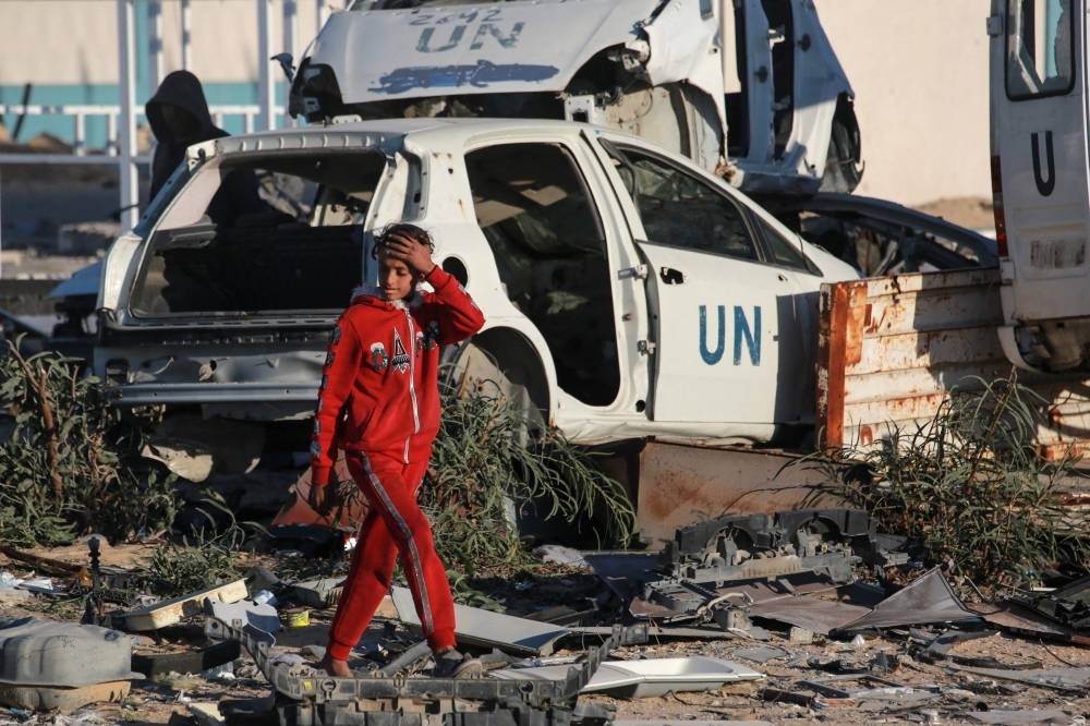 A girl walks past destroyed United Nations (UN) vehicles in a ruined neighbourhood of Gaza's southern city of Rafah on Monday, as residents return following a ceasefire deal a day earlier between Israel and the Palestinian Hamas group. AFP