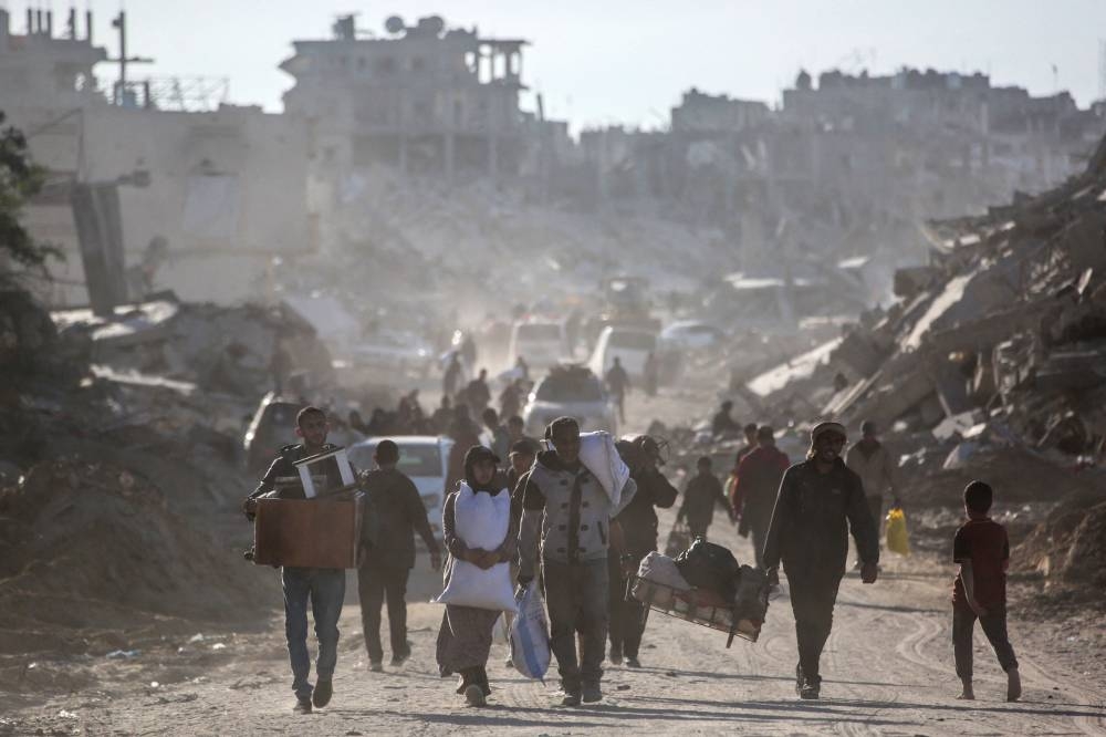 Palestinians carry belongings amidst building rubble in a ruined neighbourhood of Gaza's southern city of Rafah on Monday, as residents return following a ceasefire deal a day earlier between Israel and the Palestinian Hamas group. AFP