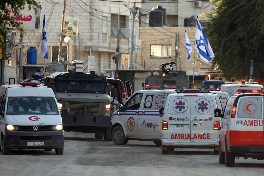 Israeli forces in armoured vehicles stop Palestinian ambulances for a search as they block a road during a military raid in Jenin in the occupied West Bank, on Tuesday. AFP