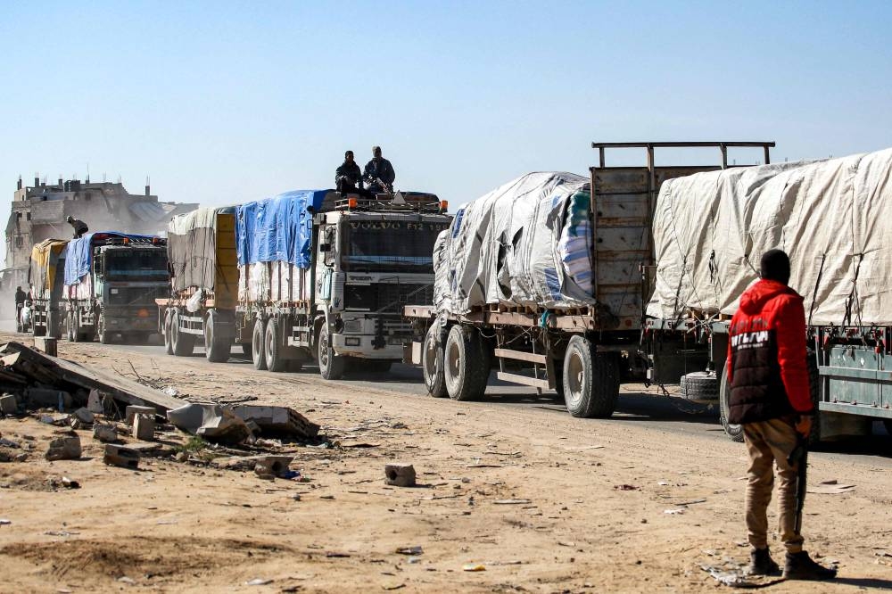 Members of security forces loyal to Hamas sit atop trucks carrying humanitarian aid coming in from the Kerem Shalom border crossing (also known as Karem Abu Salem) and arriving in al-Shoka, east of Rafah in the southern Gaza Strip, on Tuesday. AFP