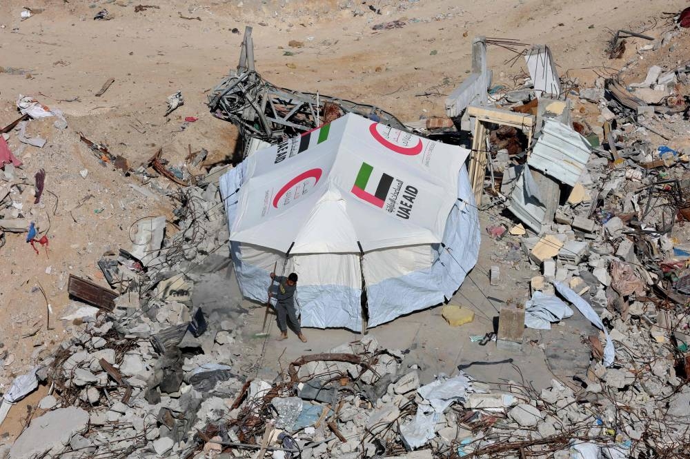 A Palestinian boy sweeps in front of a newly erected tent set up near the rubble of houses as displaced people return to Jabalia in the northern Gaza Strip, Tuesday, on the third day of a ceasefire deal in the war between Israel and Hamas in the Gaza Strip. AFP
