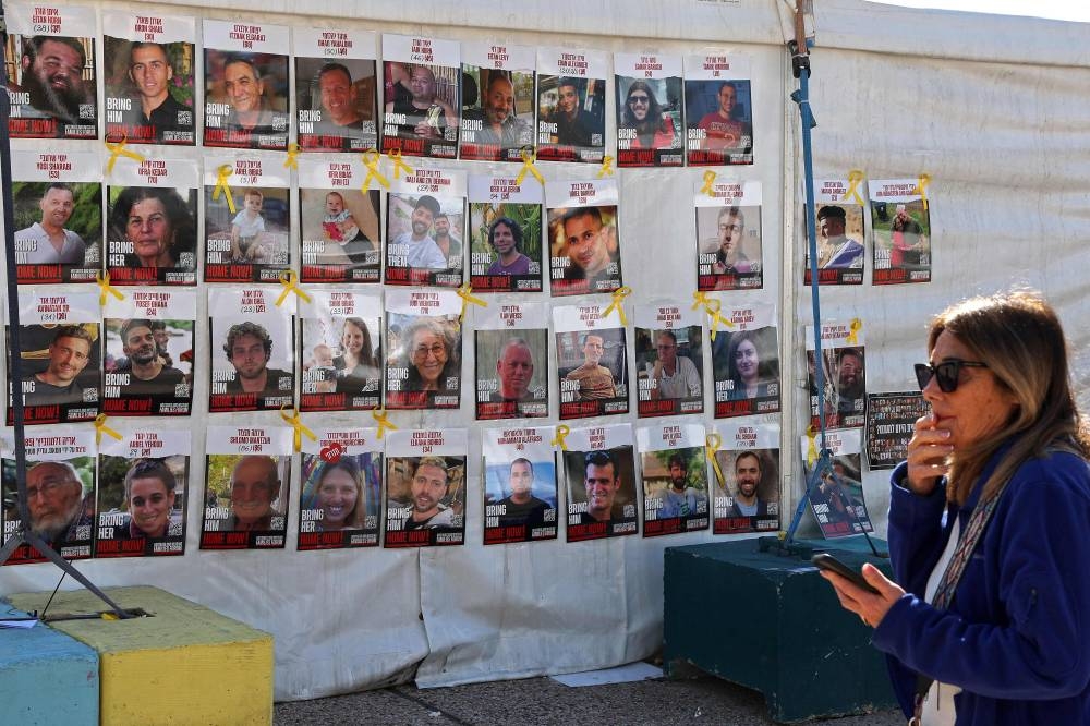 A woman walks past the portraits of Israeli captives displayed on a tent at the main gathering place for families of hostages, in Tel Aviv on Tuesday. AFP