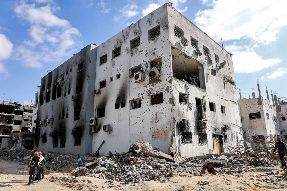 People stand outside the heavily-damaged Kamal Adwan hospital in Beit Lahia in the northern Gaza Strip on Monday, a day after a ceasefire deal in the war between Israel and Hamas went into effect. AFP
