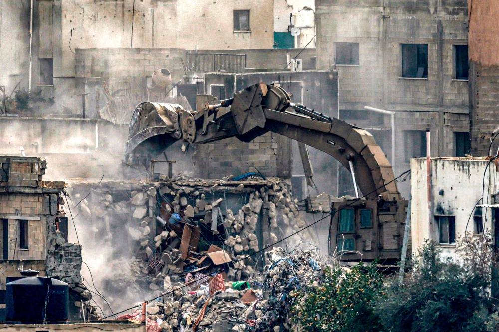 An Israeli army military excavator demolishes a building in Jenin in the occupied West Bank during a large-scale operation, on Friday. AFP