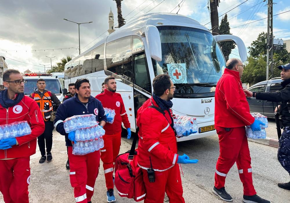 Members of the Palestine Red Crescent Society (PRCS) walk next to a bus carrying freed Palestinian prisoners after they were released from an Israeli jail, in Ramallah, in the Israeli-occupied West Bank, Saturday. REUTERS